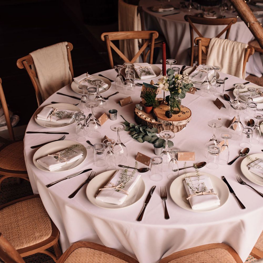 Circular rustic wedding table with wooden chairs and rustic decor
