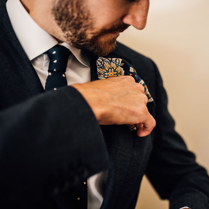 Groom does up his buttonhole on the day of his wedding