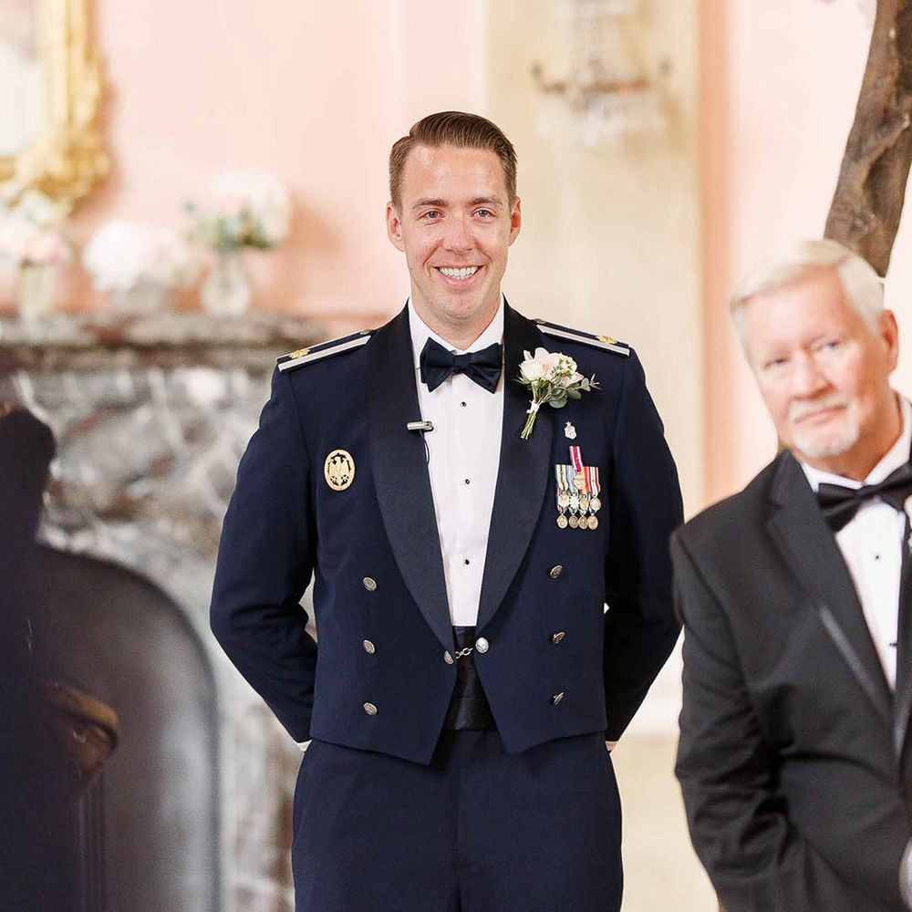 Groom waits at the end of the aisle wearing Military Uniform on his wedding day
