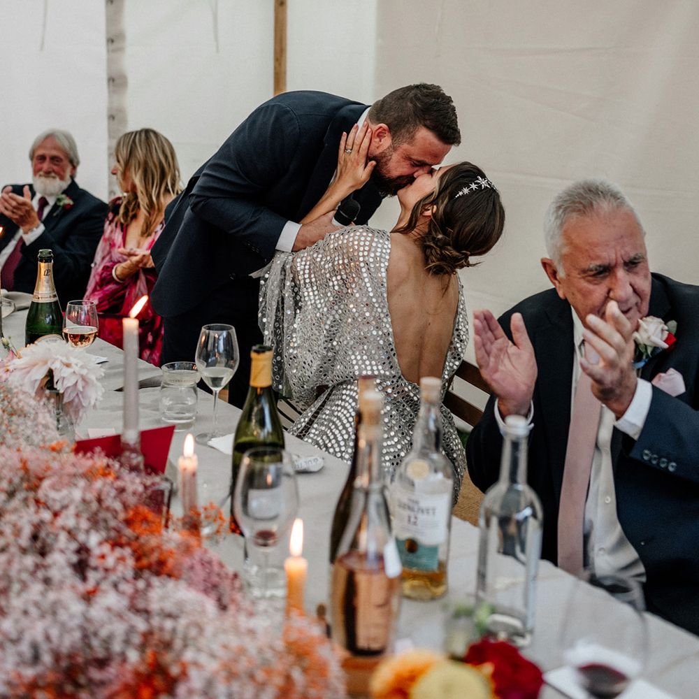 Groom kissing his bride during the marquee wedding speeches 