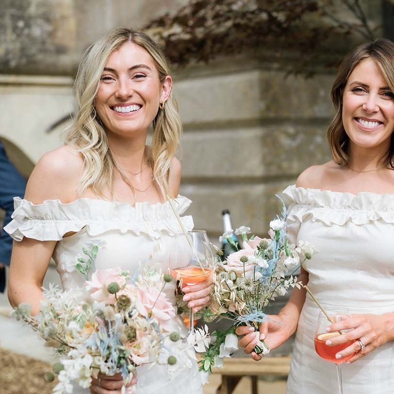 Bridesmaids with curled hair, off the shoulder puff sleeve off white dresses and pastel pink, blue and white bouquets