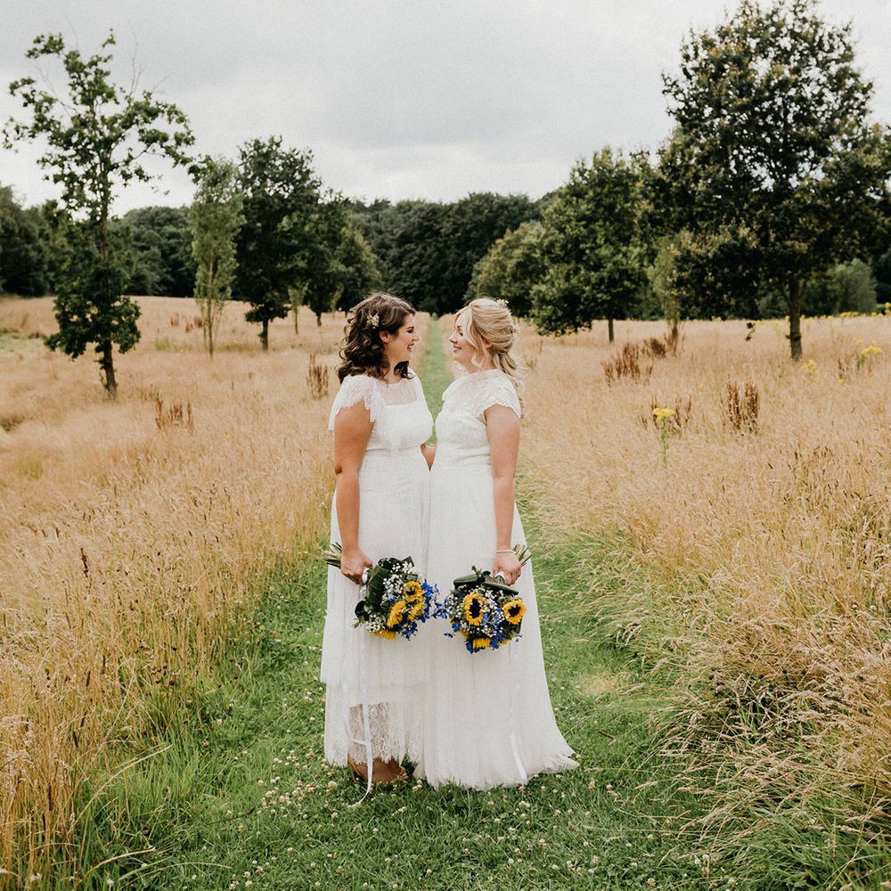 Brides stand facing each other after outdoor ceremony at Chaucer Barn 
