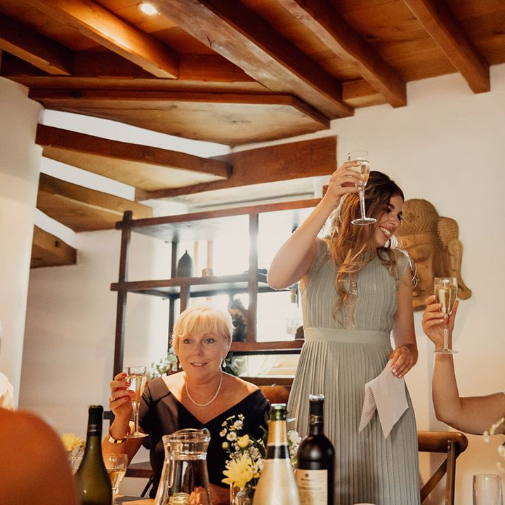 Bridesmaid in pleated green dress does a speech and holds a toast for the newlyweds 