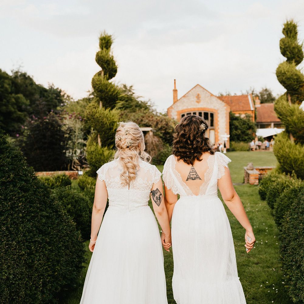 Brides walk towards their venue together with cool tattoos 