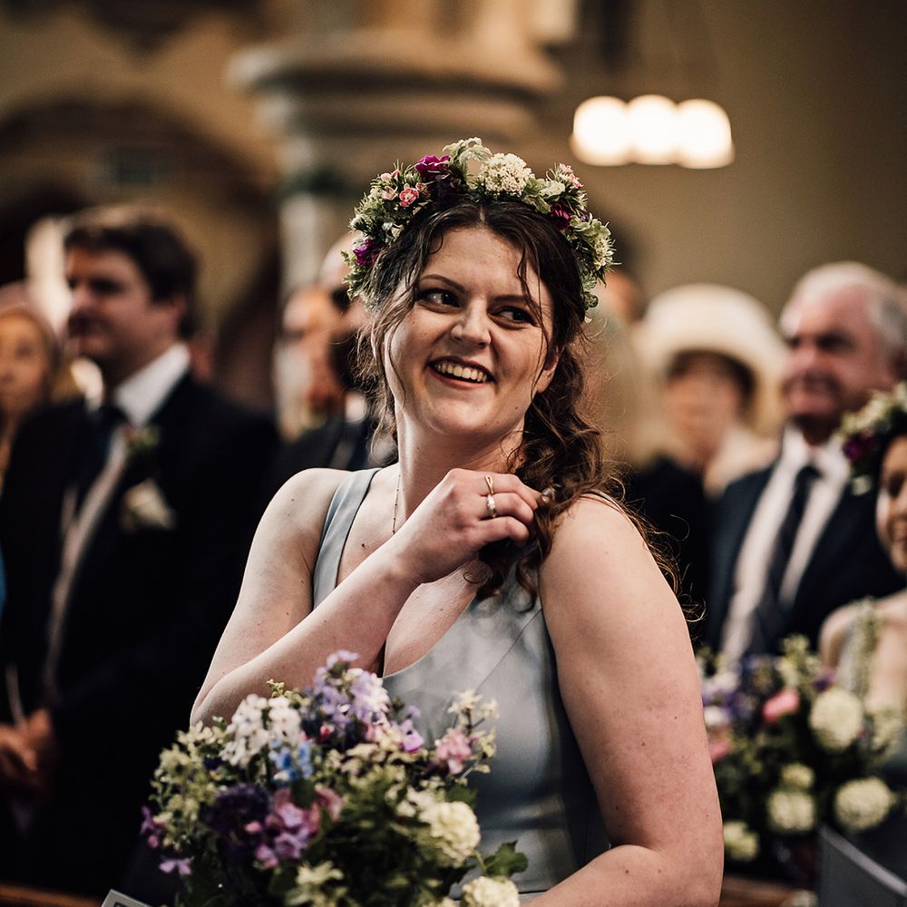 Bridesmaid wearing flower crown, purple and white wedding bouquet and green dress 