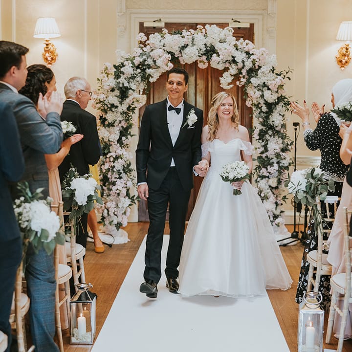 Bride and groom walk back down the aisle as a married couple for traditional style wedding 