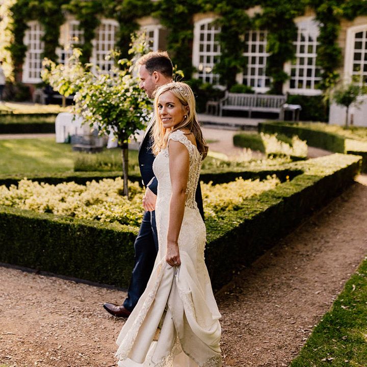 Bride in lace wedding dress looks at the camera as she walks around the gardens of Goldney Hall 