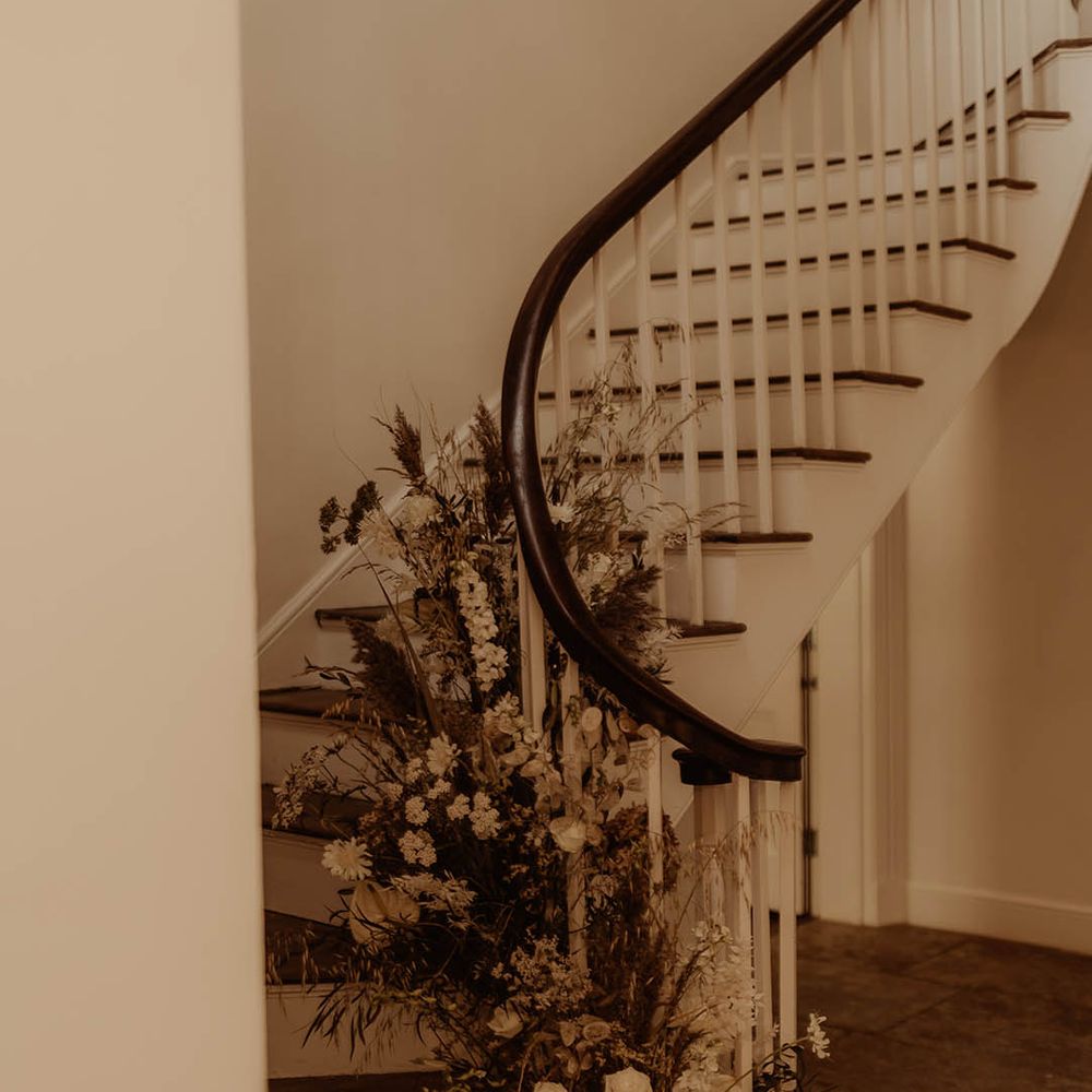 White and neutral fresh and dried flowers on a staircase for boho luxe wedding 