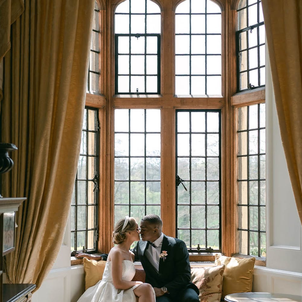 Bride and groom sit together at Ruston Hall and lean in for a kiss for their classic country house wedding 