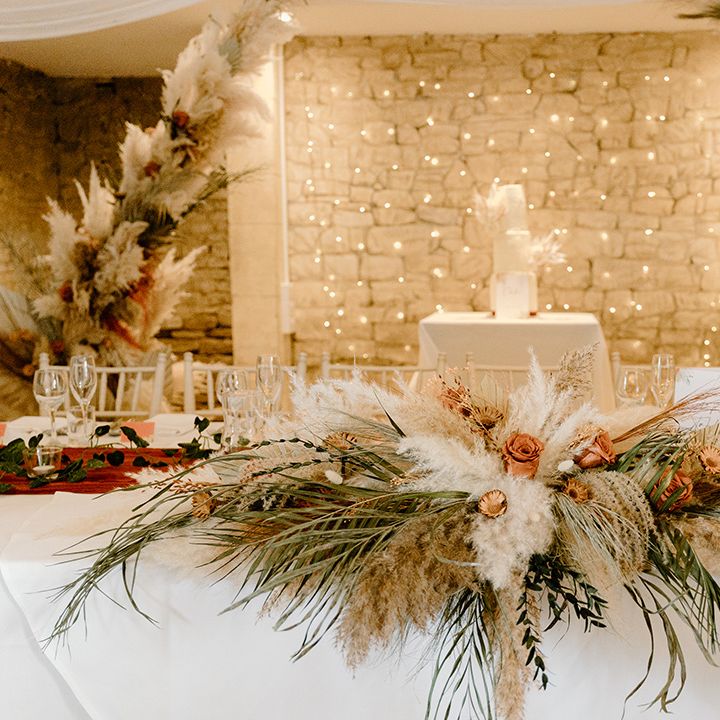 The top table decorated with pampas grass and other dried flowers along with fairy lights 