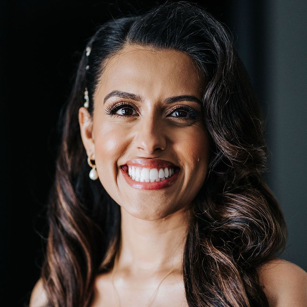 Indian bride wears her hair in loose waves complete with pearl drop necklace and sweetheart neckline lace wedding dress 