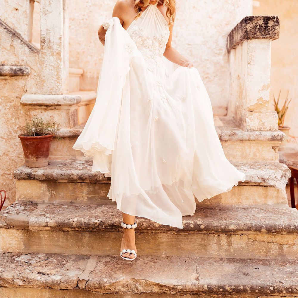 Bride with her blonde hair in a half up half down style in a flower halter neck wedding dress for a destination wedding 