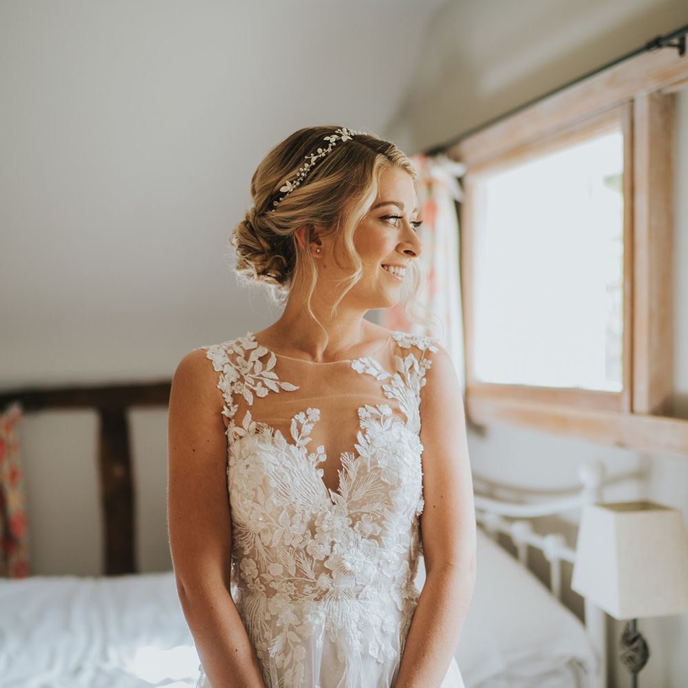 Bride in an illusion lace Dandon London wedding dress with her hair in a braided blonde updo with sparkly headpiece 