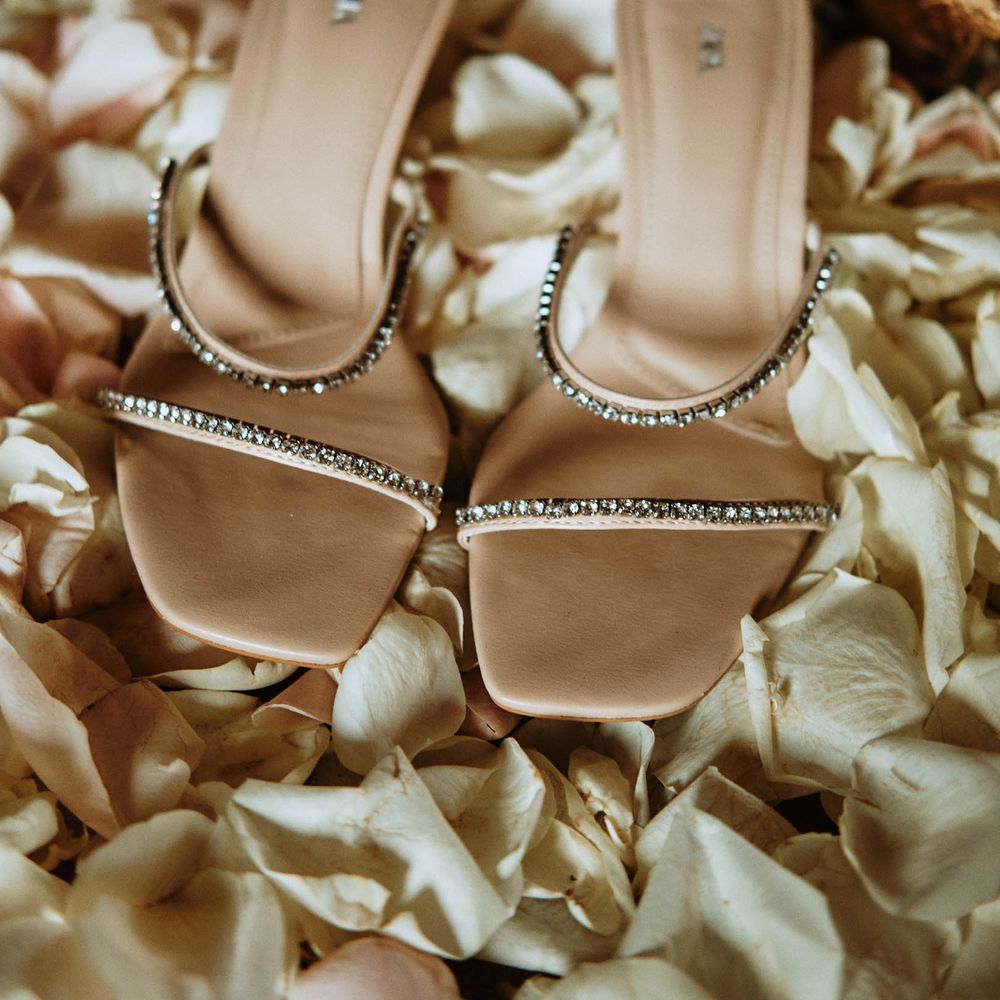 Sparkly nude bridal shoes surrounded by pastel petals