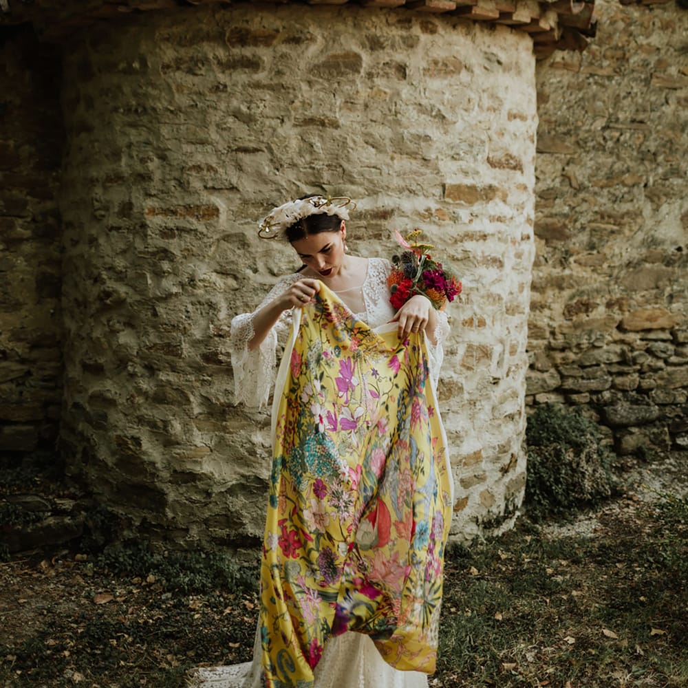 Bride in lace wedding dress and bridal crown carrying bright pink bridal bouquet and floral yellow pashmina