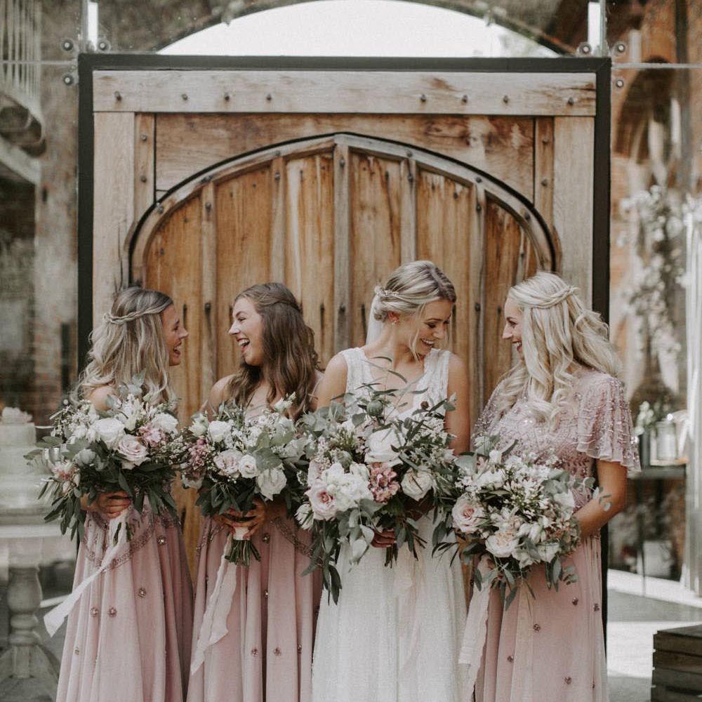Bride standing with bridal party wearing short sleeve midi embellished bridesmaid dresses at Shustoke Barn wedding