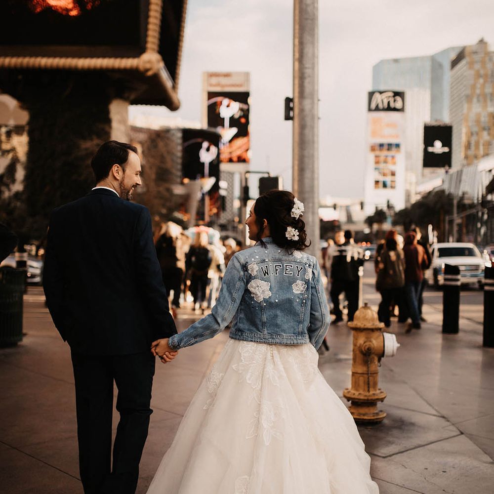 Bride wearing light blue denim jacket with pearls, white flowers and letters spelling out 'WIFEY' for Las Vegas wedding 