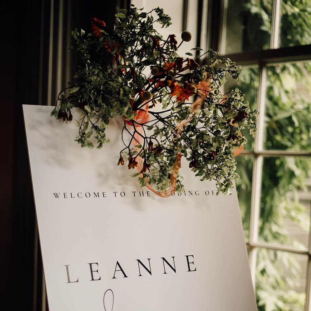 Black and white minimal wedding welcome sign decorated with foliage for classic wedding  