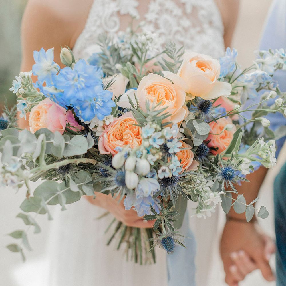 Orange roses in bouquet with blue flowers and foliage 