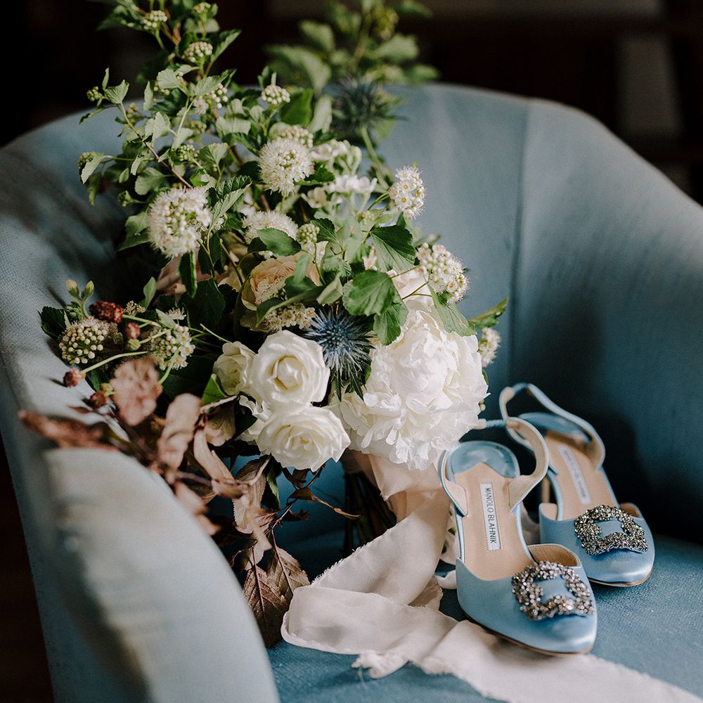 Light blue Manolo Blahnik wedding shoes on armchair with wedding bouquet 