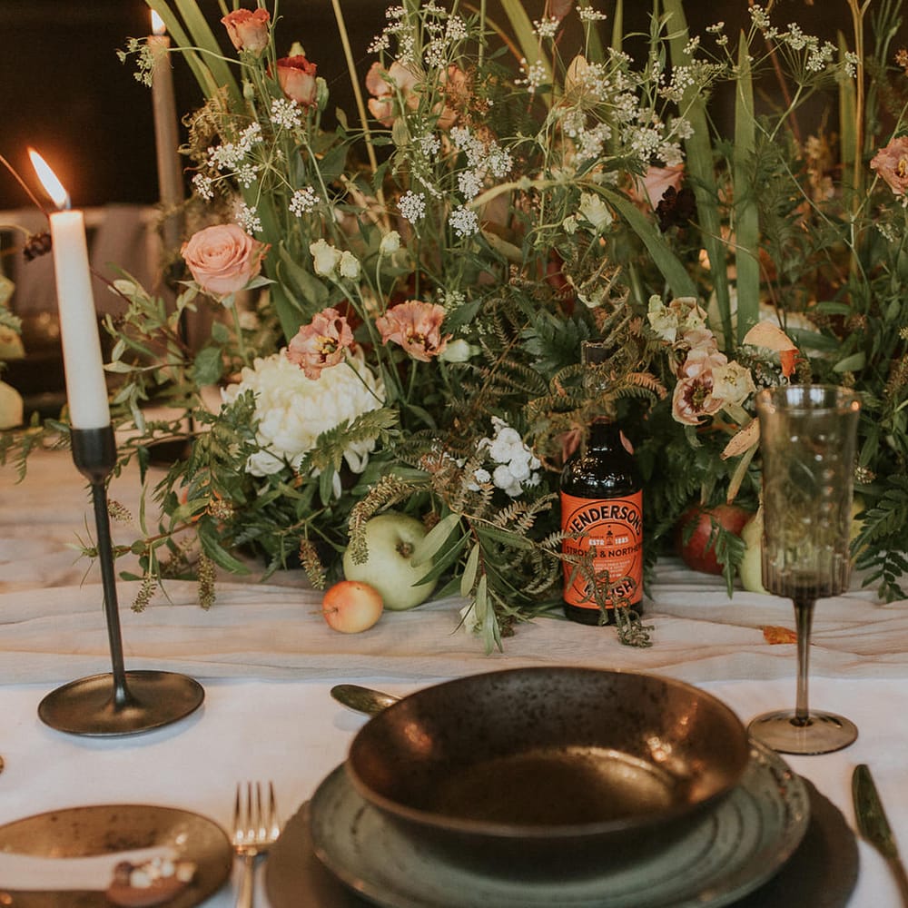 Place setting with coloured tableware, floral centrepiece and candles 