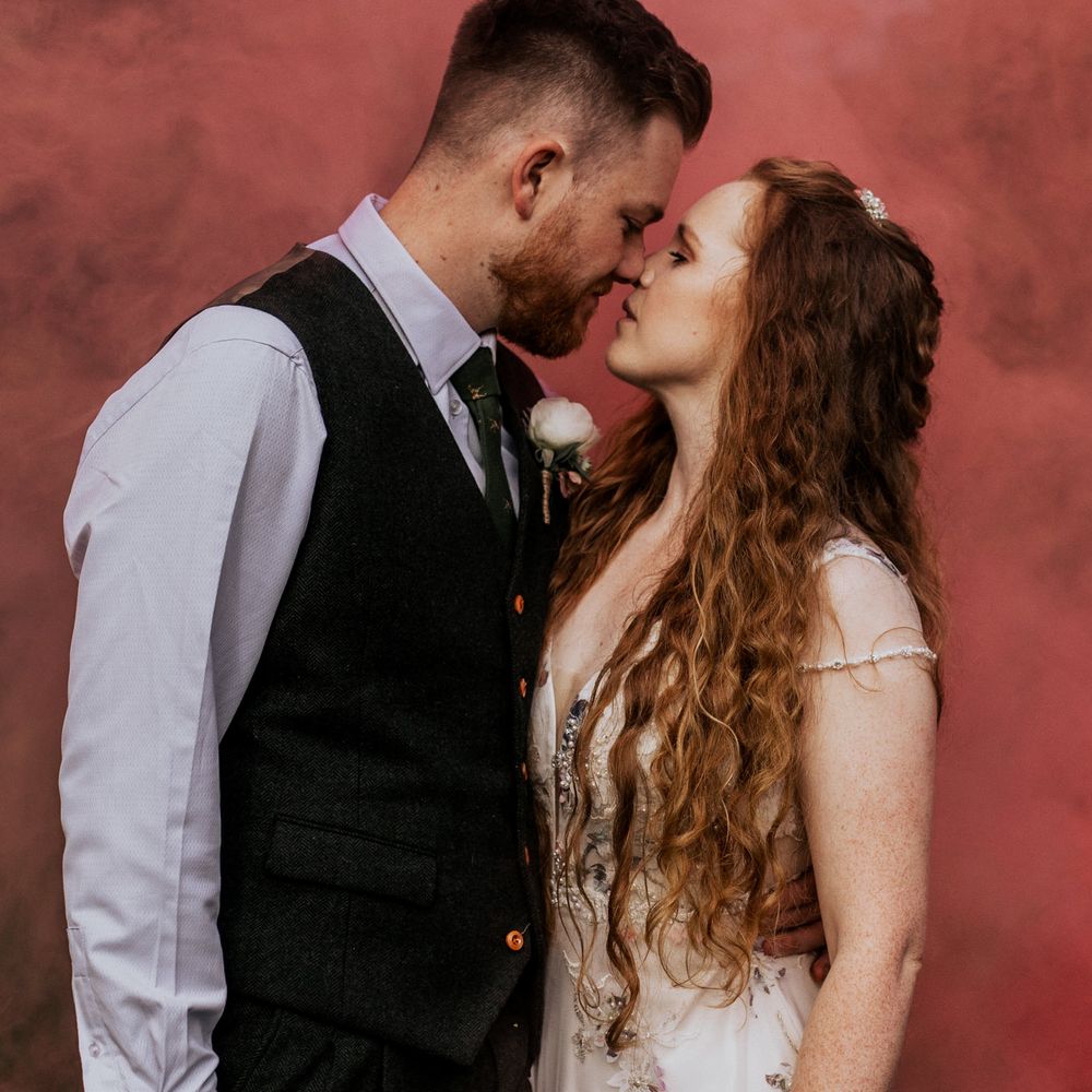 Bride & groom kiss in front of pink smoke bomb 