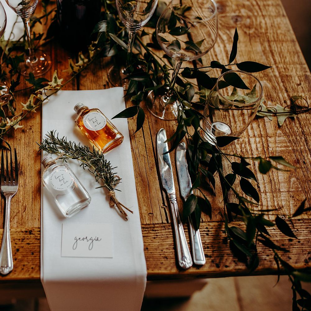 Rustic table decor with white wedding stationery and green foliage