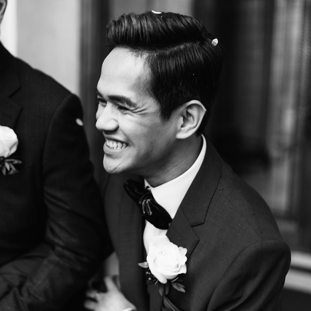 Black & white image of grooms laughing 