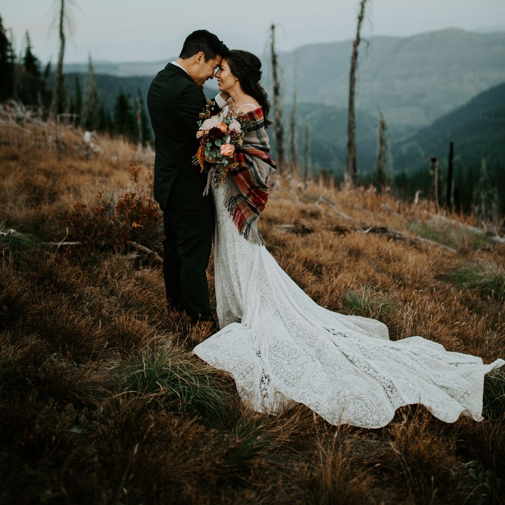 Bride & groom touch foreheads on mountain top 
