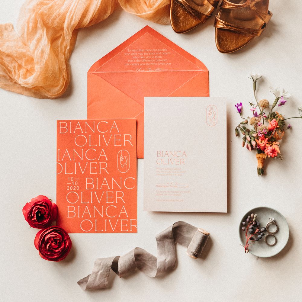 Orange & white wedding stationery surrounded by floral decoration