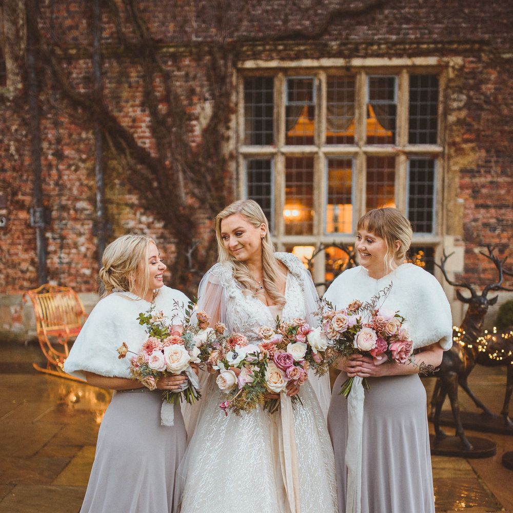 Bridal party portrait with bridesmaids in grey dress and white faux fur stoles holding blush pink and white wedding bouquets at Goldsborough Hall wedding