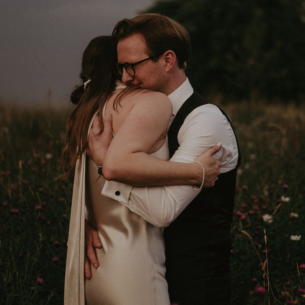Bride & groom hug outdoors on the day of their wedding within the countryside