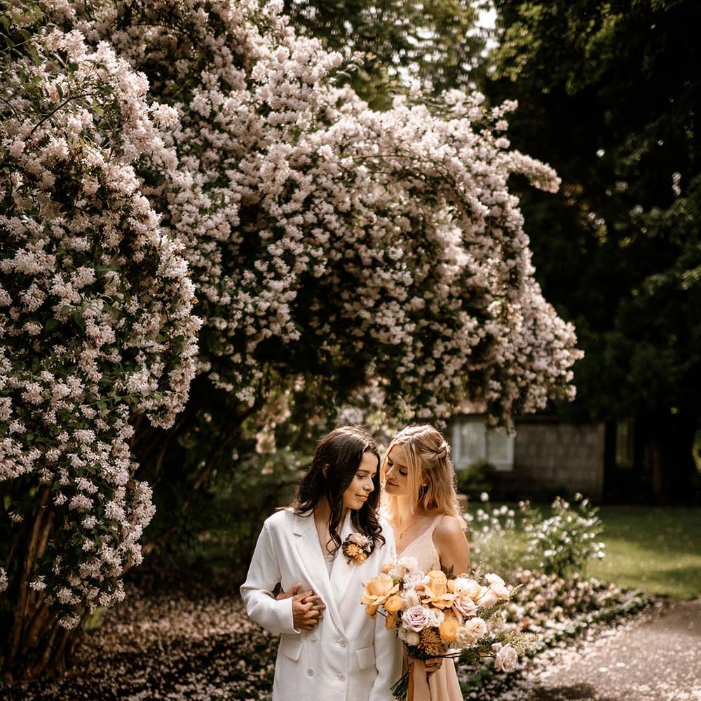 Couples portraits under a blossom tree with bride in a white suit and blush wedding dress