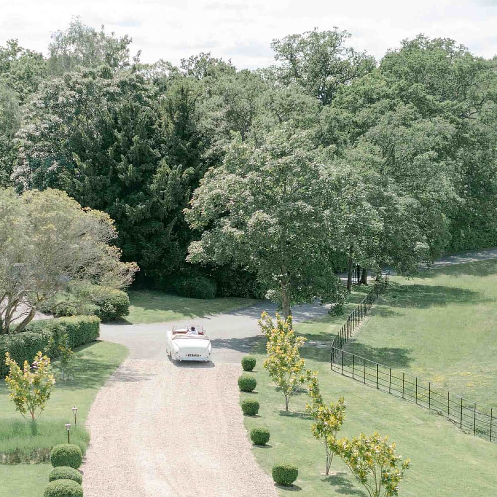 Bride and groom driving a vintage 1951 British Bentley Franay wedding car along the driveway at Botley's Mansion, Surrey