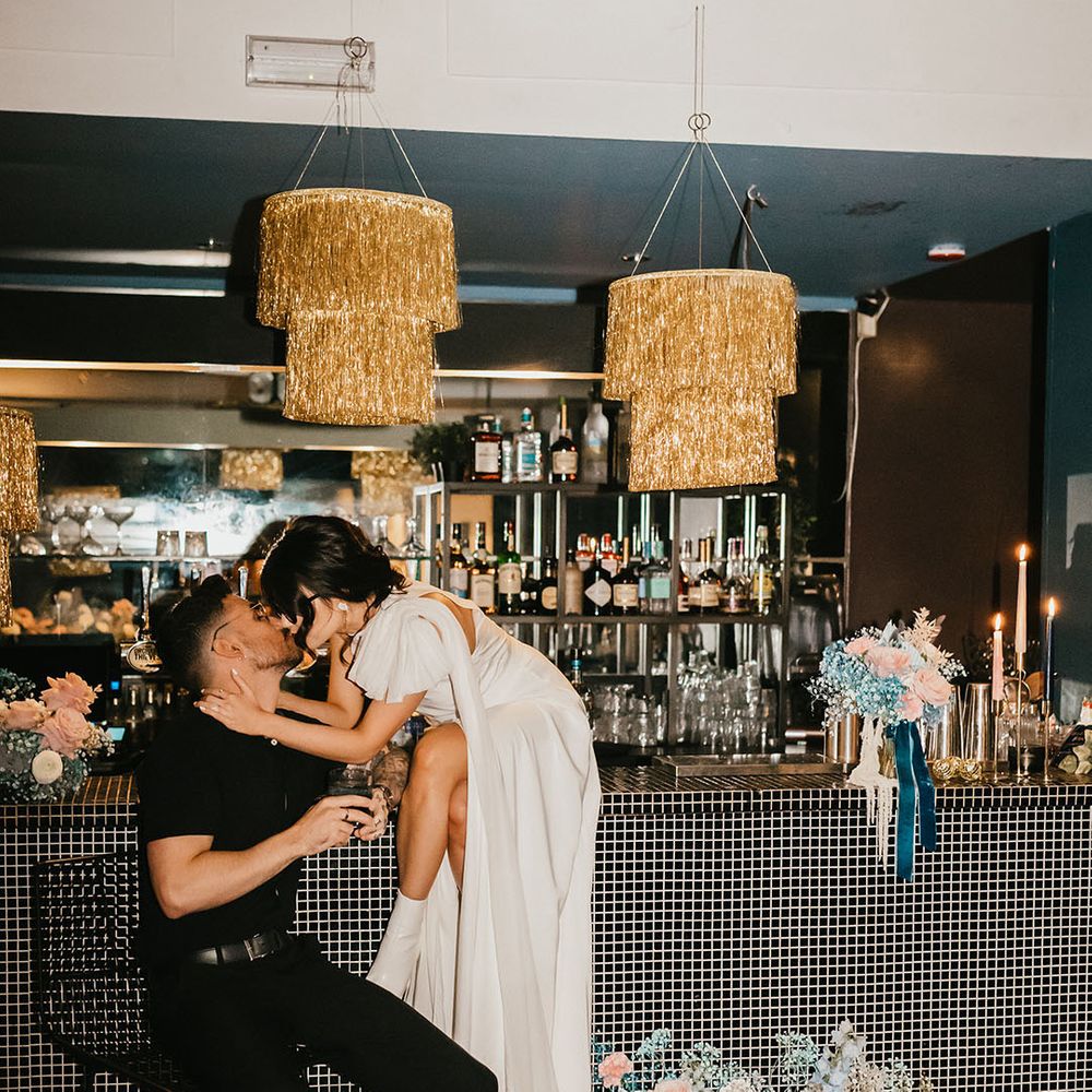 Bride kissing her grommet the stylish bar wedding wedding reception with gold glitter balls 