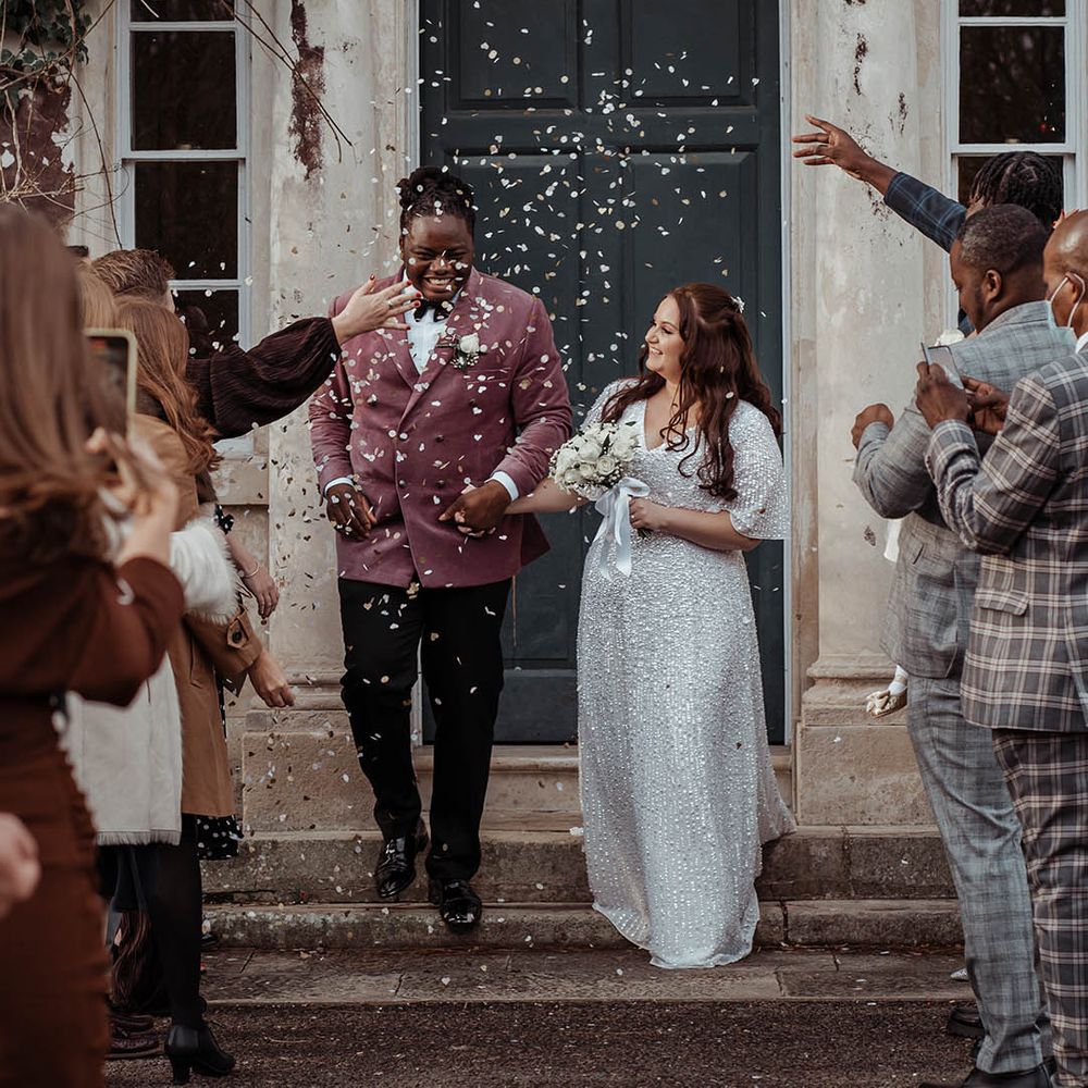 Bride & groom leave ceremony as wedding guests throw confetti around them 