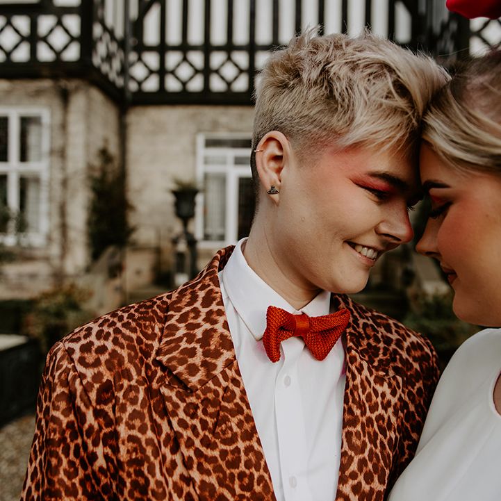 Bride with short blonde hair wearing a leopard print suit, red bowtie and eyeshadow 