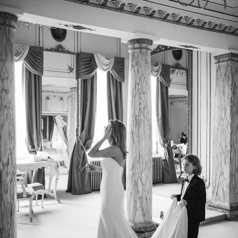 Son holds train of bridal gown during wedding day