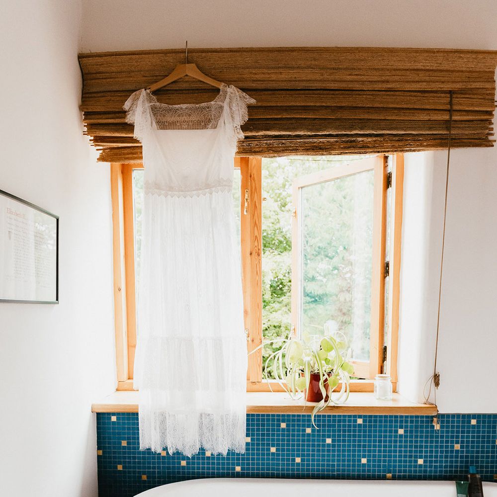 White wedding dress with sheer lace neck hangs over bathtub