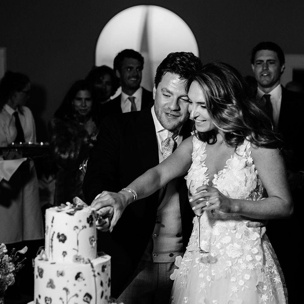 Bride and groom cut their three tier wedding cake with flowers 