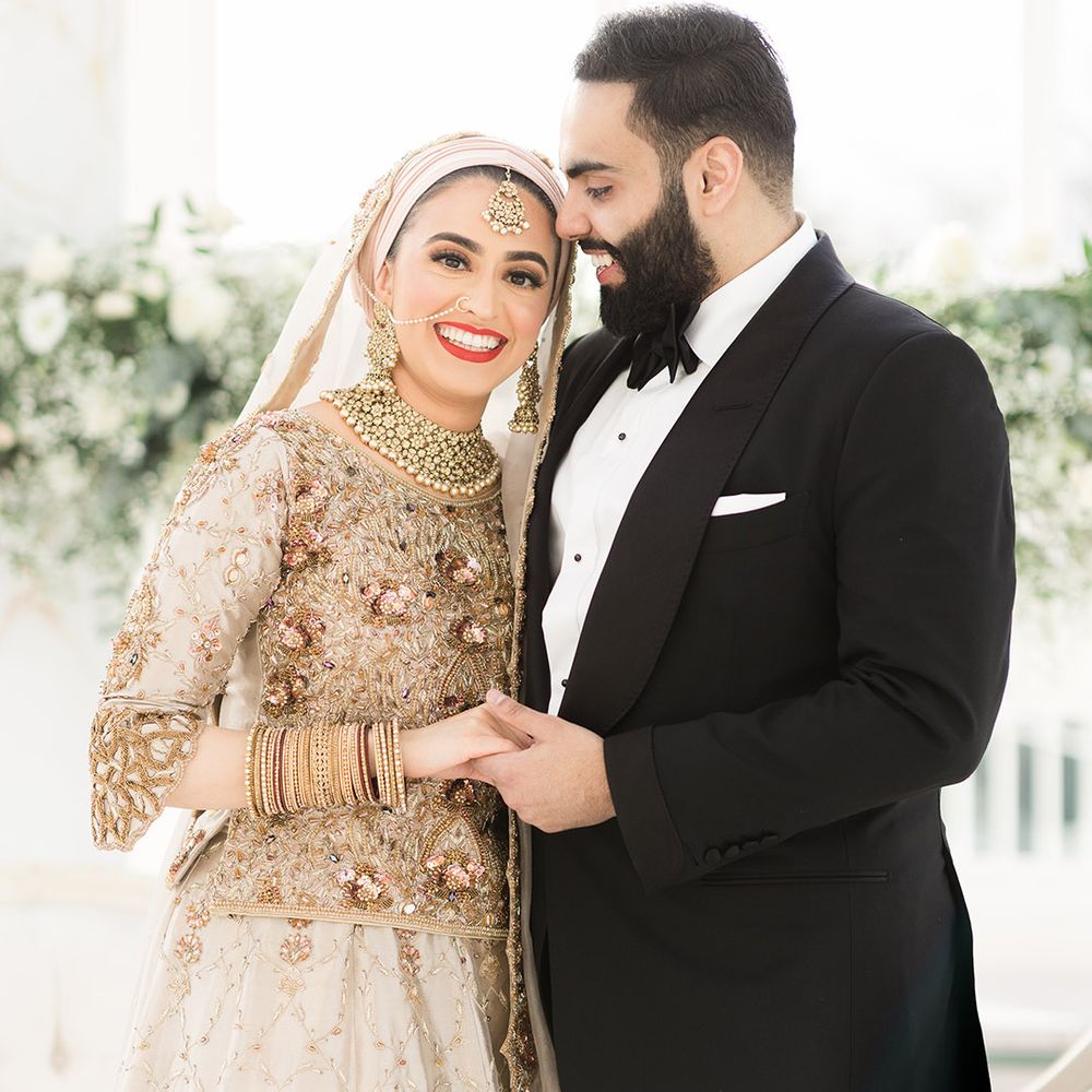 Bride wears traditional saree in gold and silver whilst leaning into her groom who wears black tie for Nikkah & Walima 