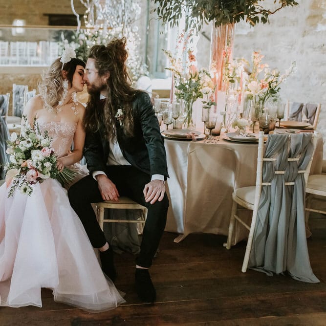 Bride in a pink strapless wedding dress kissing her groom in a black tuxedo during their Tithe barn wedding reception at Hooton Pagnell 