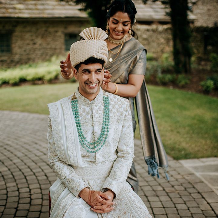 Family member helps dress groom outdoors before Haldi ceremony 