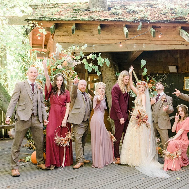 Bride & groom stand with their groomsmen in tartan suits and bridesmaids in Rewritten Bridesmaid dresses 