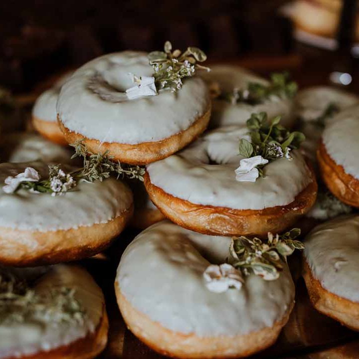Sage green wedding donut tower with edible foliage and rose decorations on top 