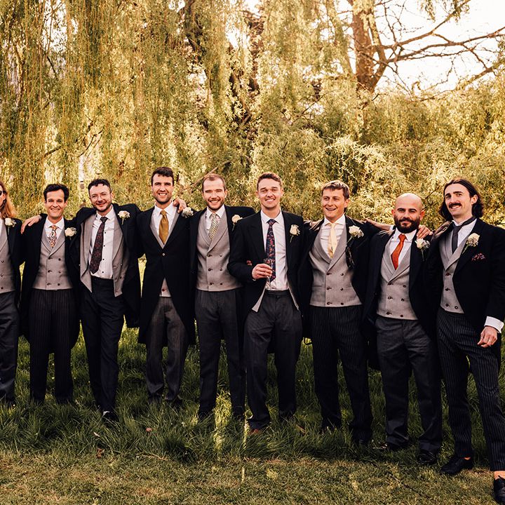 Groomsmen in mismatched morning suits with different coloured ties for spring wedding 