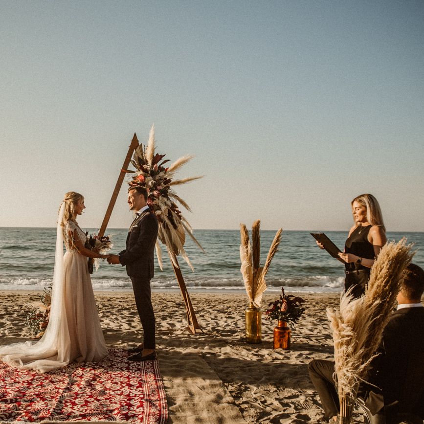 Beach wedding ceremony with rugs for the aisle