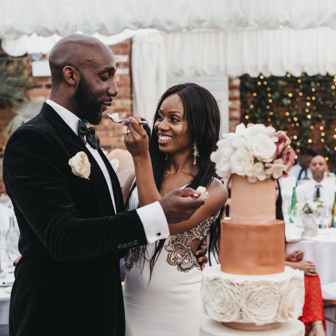 Black bride and groom feeding each other cake at the wedding cake cutting ceremony 