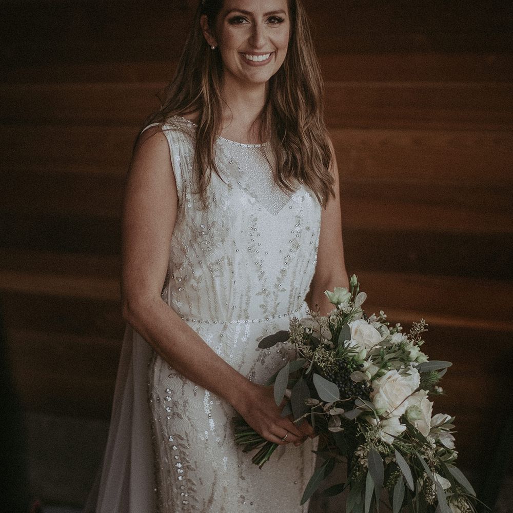 Bride holds white floral bouquet with green foliage