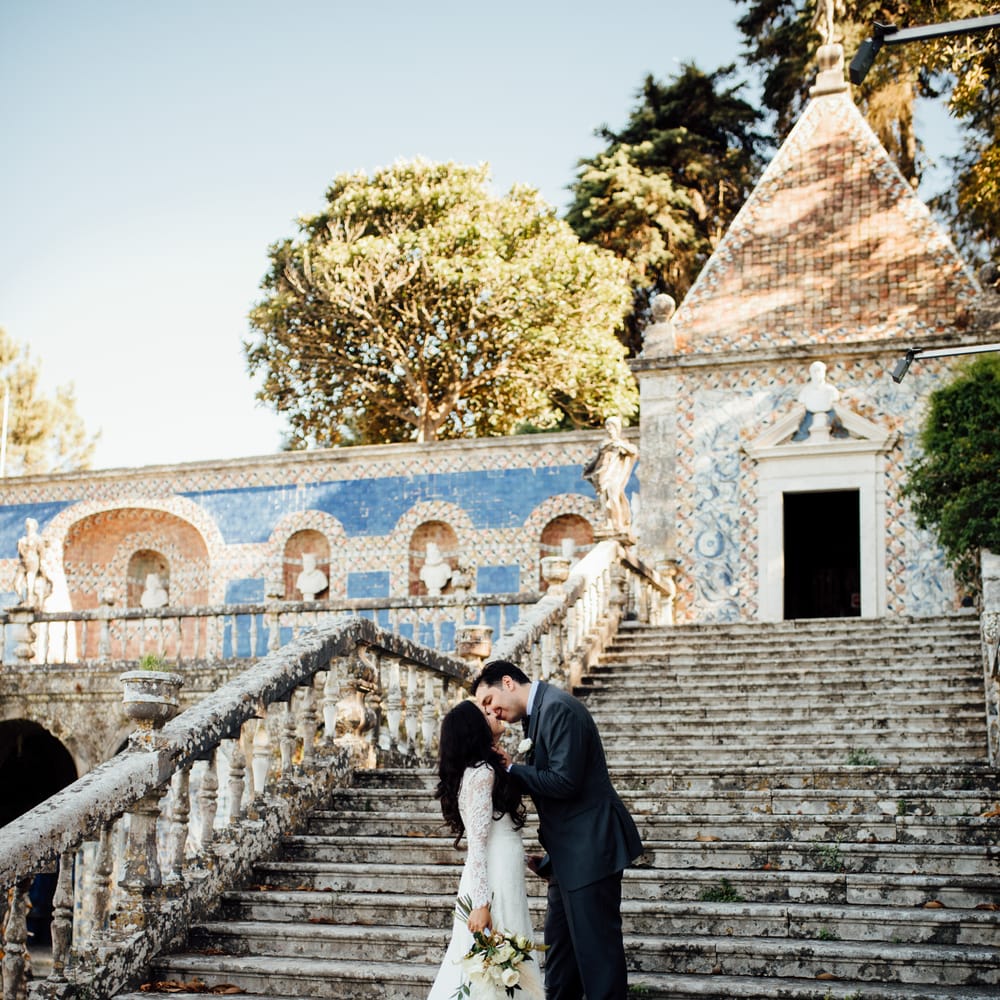 Bride & groom walk up staircase outdoors in front of colourful tiled building